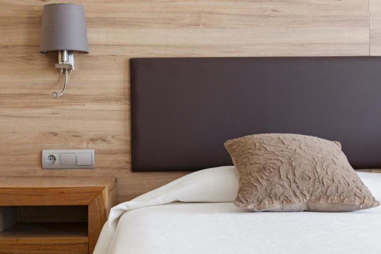 Habitación con cabecero tapizado oscuro y pared de madera natural en Hotel Cap Roig & Spa by Brava Hoteles