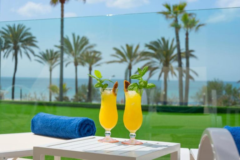 Dos cócteles tropicales en terraza con vistas al mar y palmeras del HSM Golden Playa