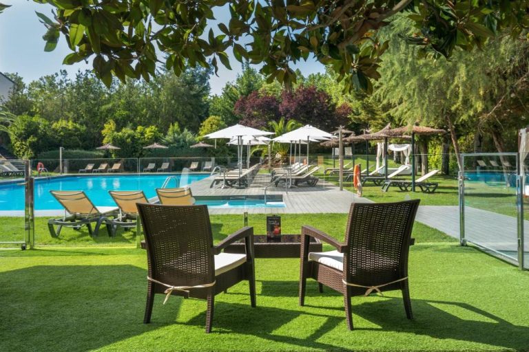 Piscina exterior con tumbonas y jardín del Barceló Cáceres V Centenario en un día soleado