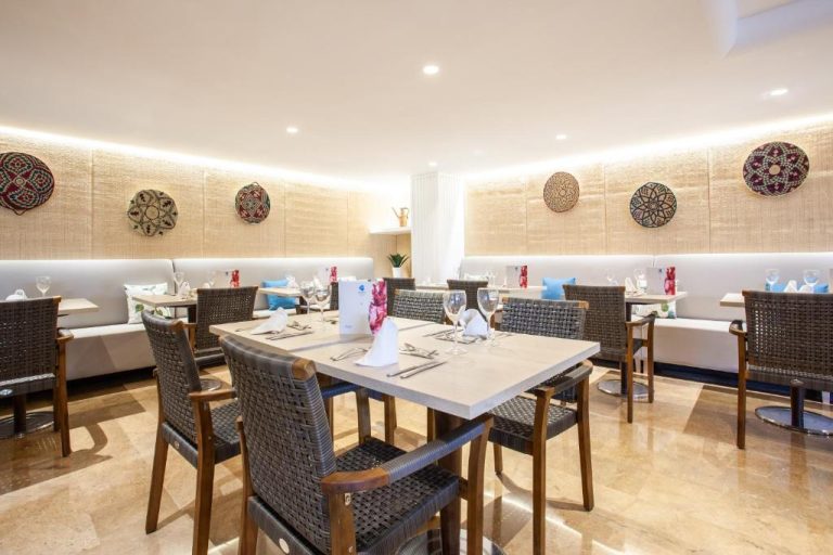 Restaurante interior elegante del Grupotel Maritimo con mesas preparadas y decoración artesanal en las paredes