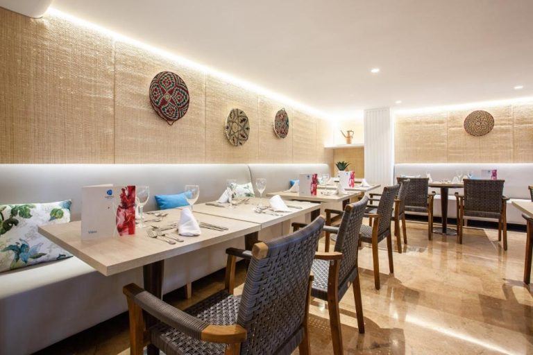 Restaurante interior del Grupotel Maritimo con mesas elegantes, sillas de mimbre y decoración artesanal en la pared