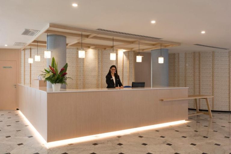 Recepción moderna del HSM Golden Playa con mostrador iluminado y personal de atención al cliente