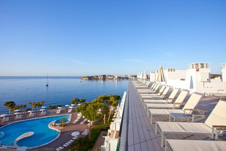 Terraza con tumbonas y piscina exterior del Aparthotel Ponent Mar con vistas al mar en Mallorca