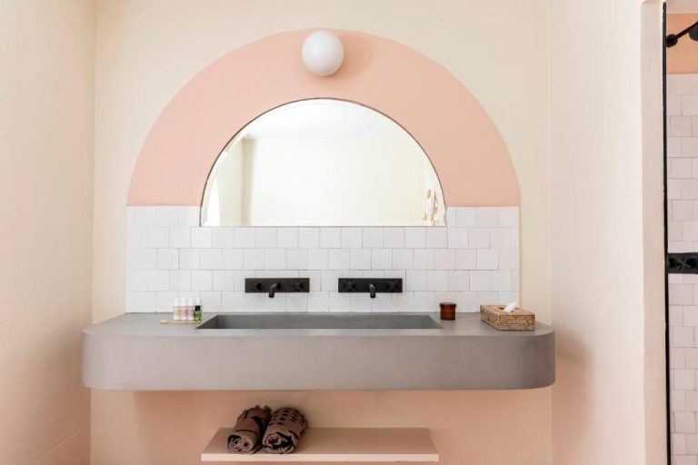 Baño de diseño con lavabo de hormigon y espejo arqueado en el Hotel Menorca Experimental