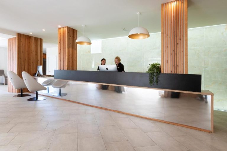 Recepción moderna del Hotel Las Arenas con mostrador negro y revestimiento de madera natural