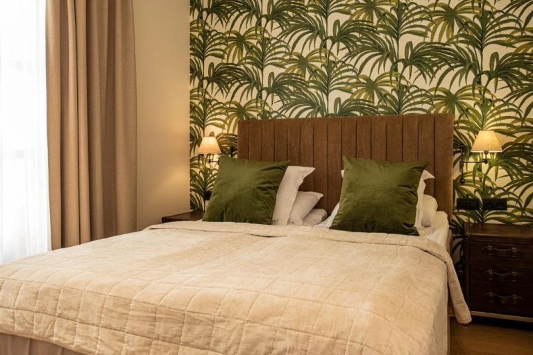 Habitación doble con cabecero de madera y papel pintado tropical en Palma Suites