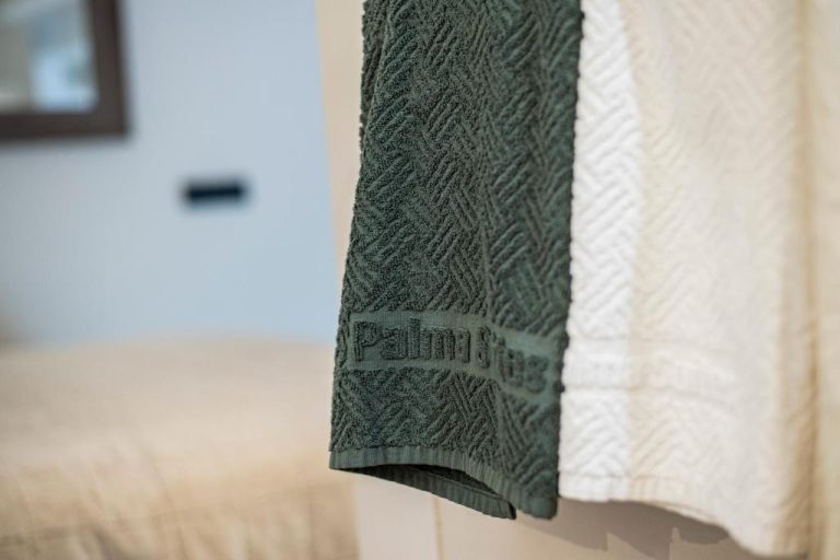Toallas de baño verdes y blancas con logo bordado en Palma Suites