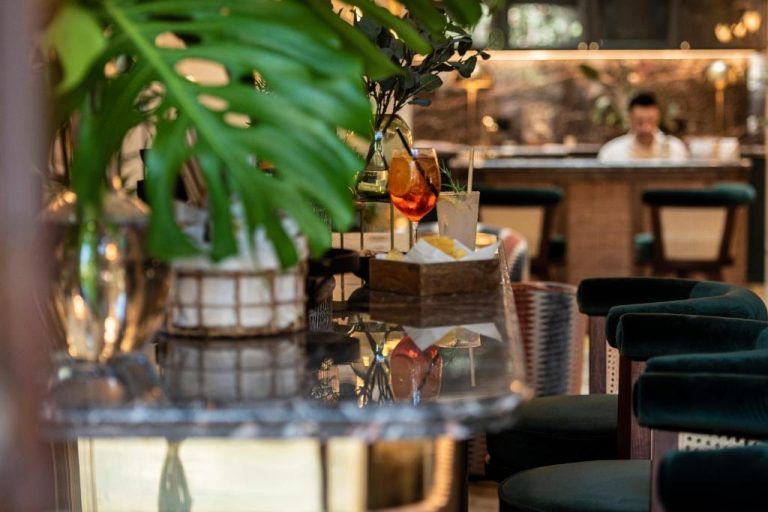 Bar con cócteles tropicales y decoración con plantas en Palma Suites, ambiente elegante y acogedor