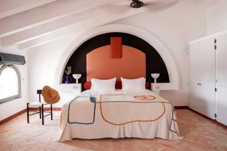 Habitación doble con arco decorativo y cabecero terracota en Menorca Experimental Hotel