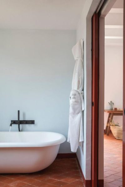 Baño con bañera exenta blanca y albornoz colgado en Menorca Experimental Hotel