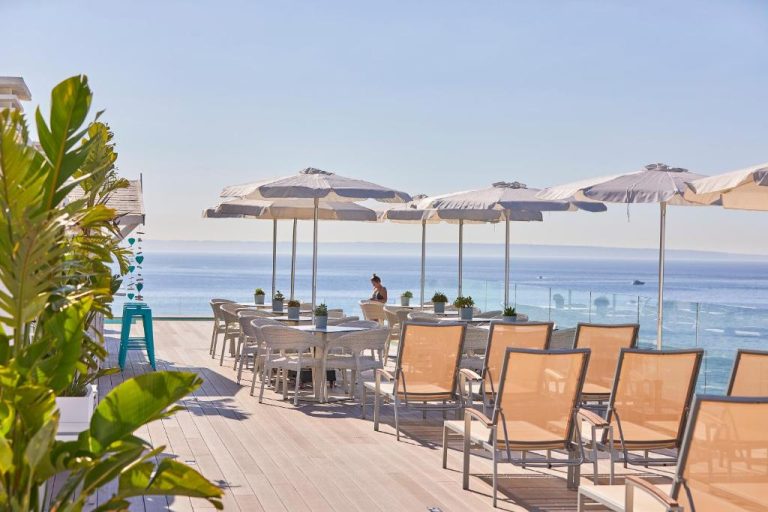 Terraza exterior con tumbonas y sombrillas blancas del Aparthotel Ponent Mar con vistas al mar
