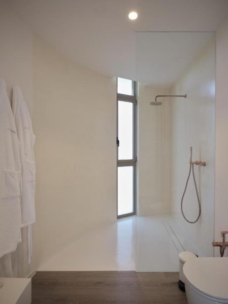 Baño minimalista con ducha de lluvia y acabados en blanco en Retiro Costiña Wellness & Villas