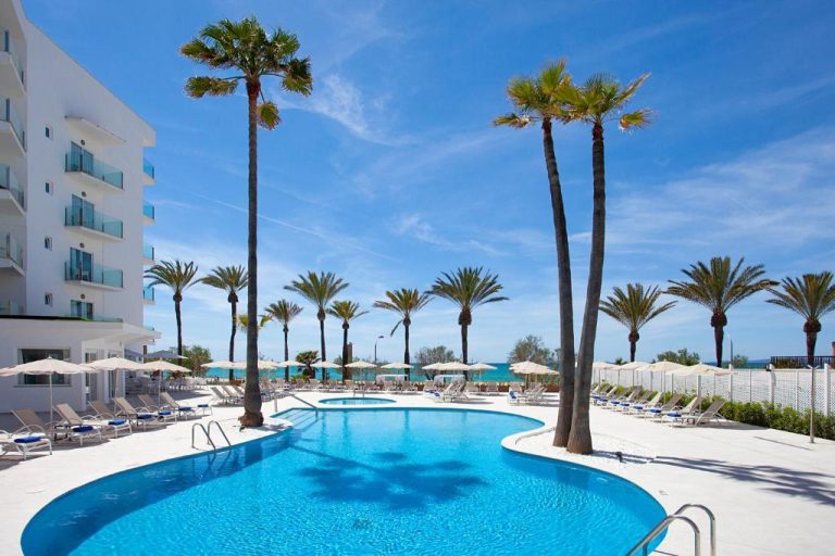 Piscina exterior rodeada de palmeras y tumbonas del Hotel HSM Golden Playa en Mallorca