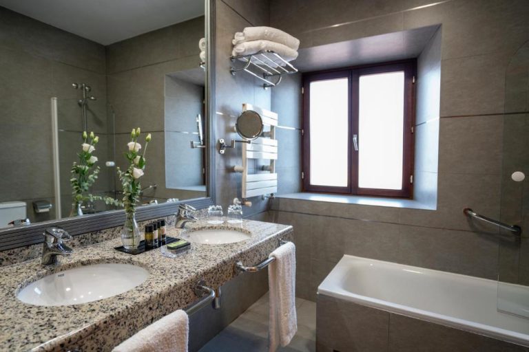 Baño de lujo con doble lavabo de mármol y bañera en Hospes Palacio de Arenales & Spa