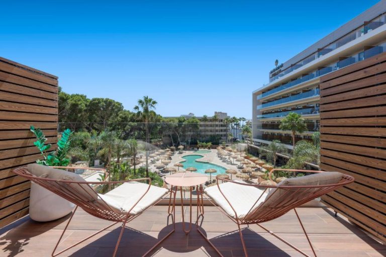 Terraza privada con sillas y vista panorámica a la piscina exterior del Aubamar Palma Resort