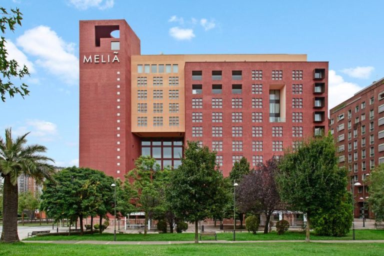 Fachada exterior del Hotel Meliá Bilbao con jardines y árboles en primer plano