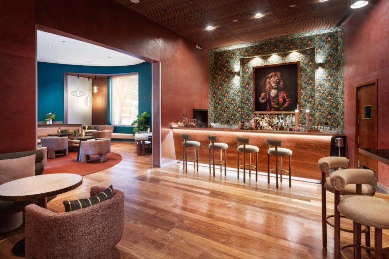 Bar lounge del Hotel Meliá Bilbao con decoración ecléctica, taburetes y pintura de león en la pared