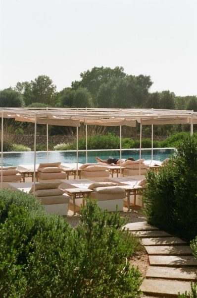 Zona de tumbonas y piscina exterior rodeada de jardín en Menorca Experimental Hotel