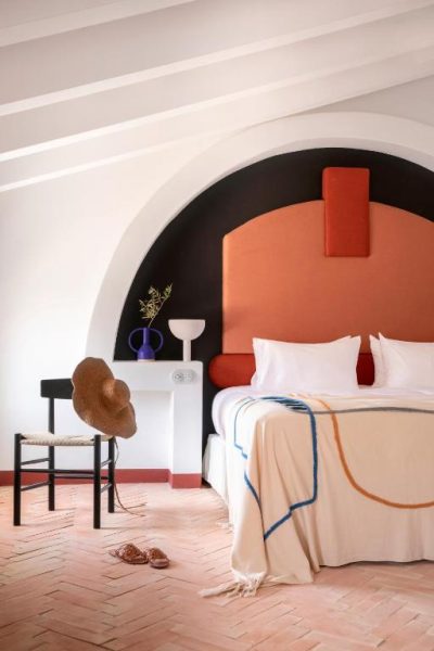 Habitación con arco decorativo en tonos terracota y suelo de barro del Menorca Experimental Hotel