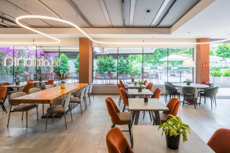 Restaurante interior con terraza exterior del Catalonia Gran Vía Bilbao con sillas naranjas y grandes ventanales