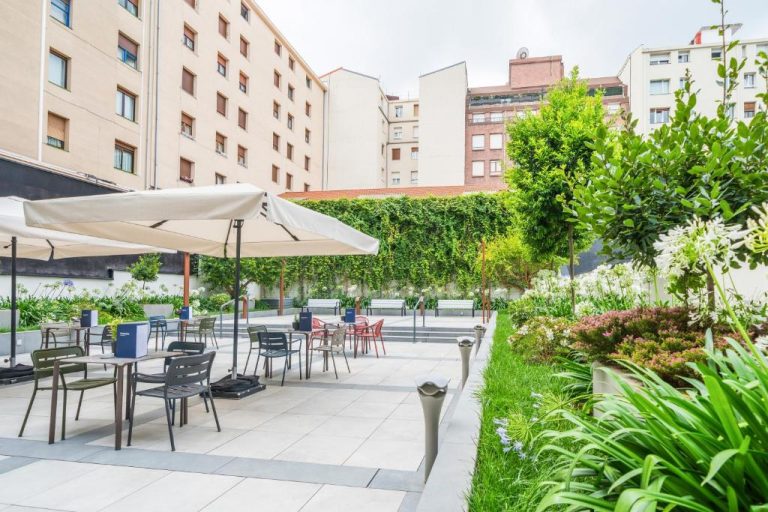 Terraza jardín exterior con mesas y sombrillas del Hotel Catalonia Gran Vía Bilbao