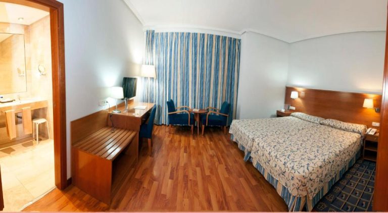 Habitación doble con suelo de madera y decoración en azul del Extremadura Hotel