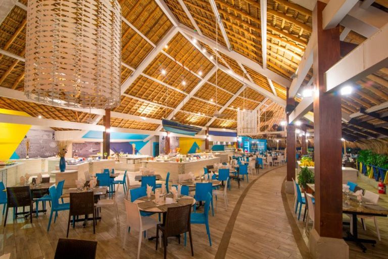 Restaurante buffet con techo de palma y sillas azules en Fiesta Resort All Inclusive Costa Rica