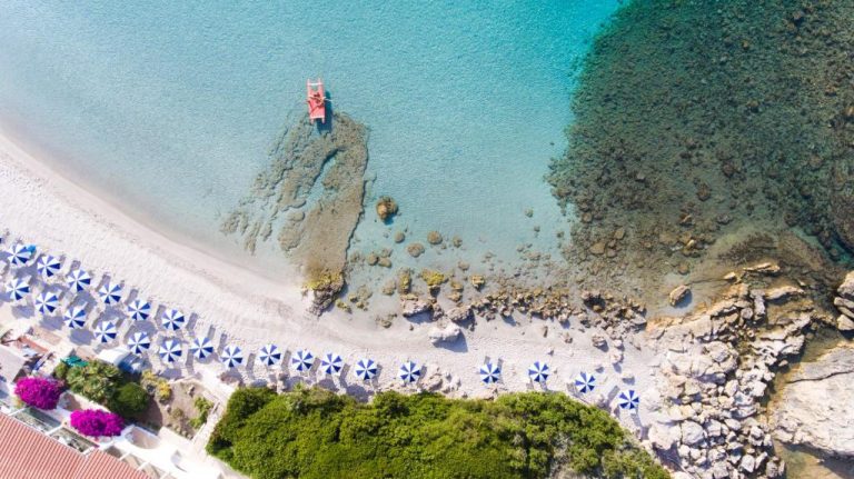 Vista aérea de la playa del Hotel Dei Pini con sombrillas azules y aguas cristalinas turquesas