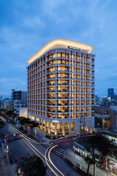Fachada exterior iluminada del JR Kyushu Hotel Blossom Naha al anochecer en Okinawa