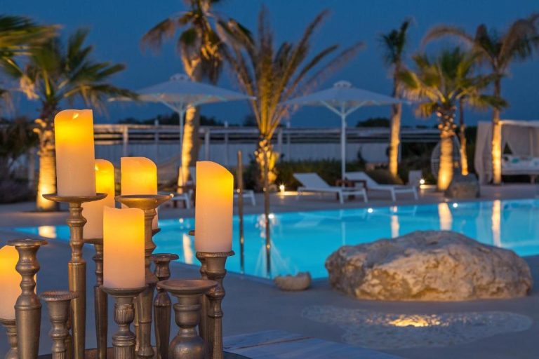 Piscina iluminada de noche con candelabros románticos en White Pearls Adults Only Luxury Suites