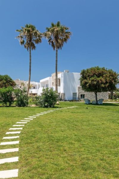 Jardín exterior con palmeras y camino de piedra blanca en White Pearls Adults Only Luxury Suites