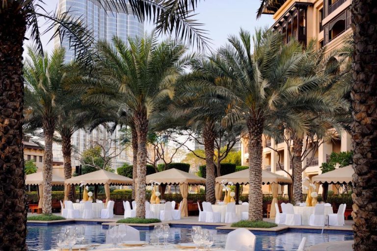 Piscina exterior con palmeras y mesas elegantes para eventos del Palace Downtown Dubai