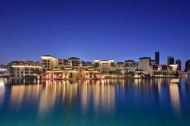Vista nocturna del Palace Downtown Dubai reflejado en el lago con iluminación dorada y arquitectura árabe