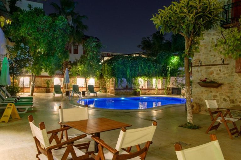 Piscina exterior iluminada de noche en el White Garden Hotel Adult Only con zona de relax