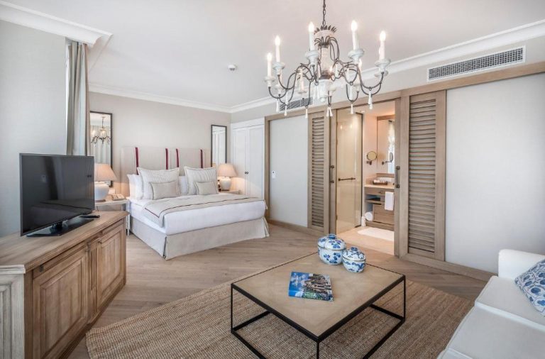 Suite deluxe con salón, cama doble y lámpara de araña elegante en Allium Bodrum Resort & Spa
