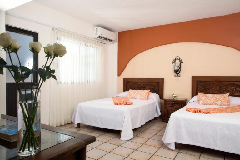 Habitación doble con dos camas y decoración colonial en Hotel El Pescador