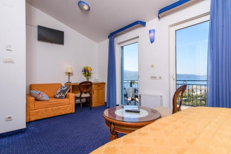 Habitación con salón, balcón y vistas al mar en Villa Mediterana con decoración azul y blanca