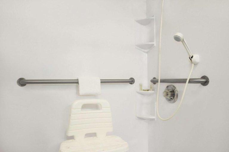 Baño adaptado con silla de ducha, barras de apoyo y teléfono de ducha en Super 8 by Wyndham Cuba