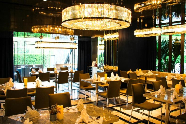 Restaurante elegante del Glam Habitat con lámparas de cristal doradas y mesas preparadas para cenar