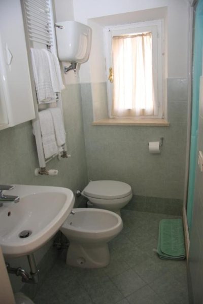 Baño completo con bidé, lavabo y ventana en el Hotel Morlacchi, decorado con azulejos verdes
