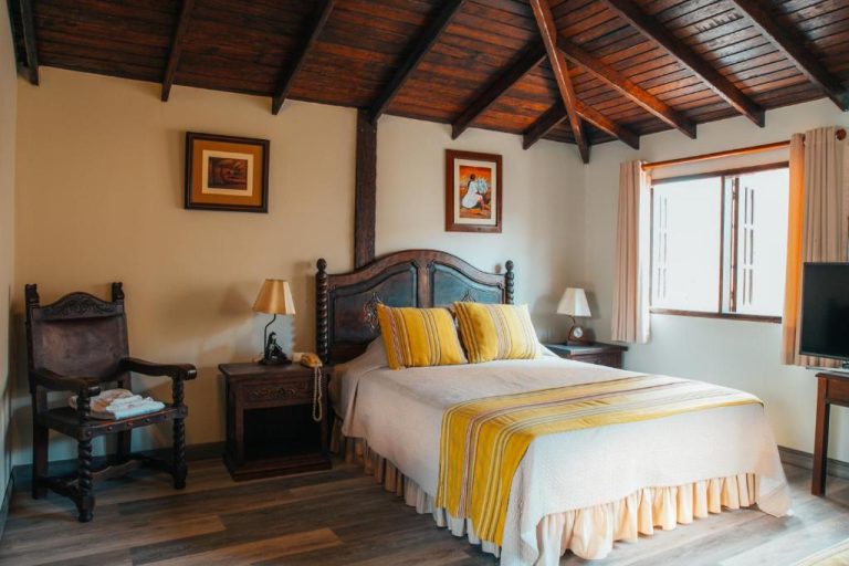 Habitación doble con cama de madera tallada y techo de vigas en Hotel Antigua Miraflores