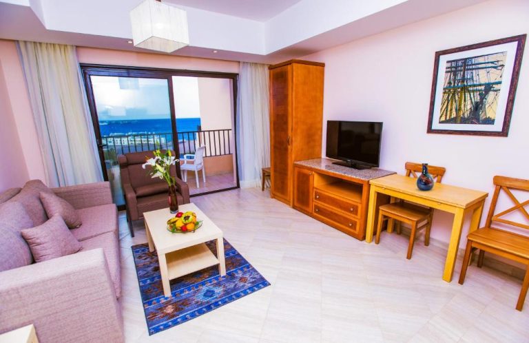 Salón amplio con sofá, mesa de comedor y balcón con vistas al mar en Sky View Suites Hotel