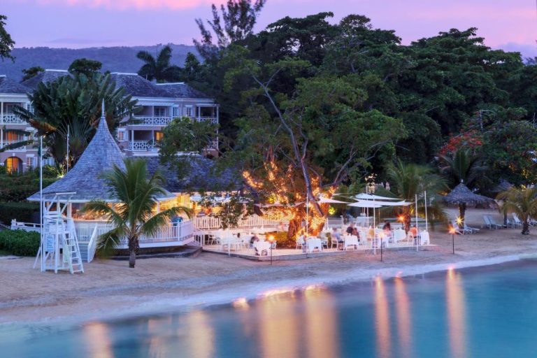 Restaurante en la playa al atardecer con luces románticas en el resort Couples Sans Souci Jamaica