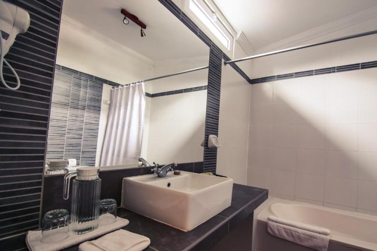 Baño completo con bañera, lavabo moderno y decoración en blanco y negro del Hotel Antigua Miraflores