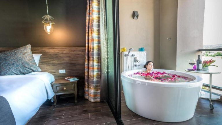 Bañera onsen con pétalos de flores en habitación del Chiangkhong Teak Garden Riverfront Onsen Hotel