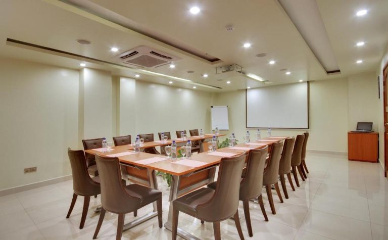 Sala de reuniones con mesa en U, sillas de cuero y pantalla de proyección en el Unima Grand