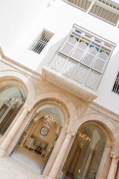 Patio interior con arcos de piedra y lámparas de araña del Dar El Jeld Hotel and Spa en Túnez