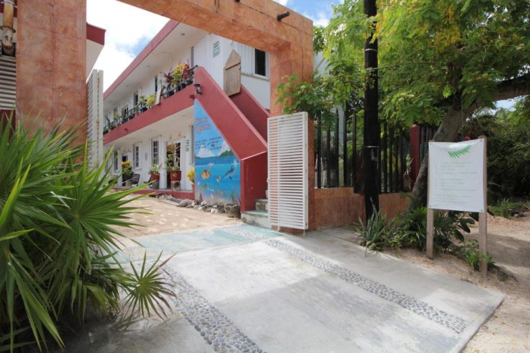 Entrada principal de Villas Roseliz con mural marino, jardines tropicales y acceso empedrado al complejo