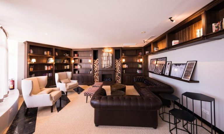 Elegante salón biblioteca con sofás de cuero y estanterías en Be Live Adults Only La Cala Boutique Hotel