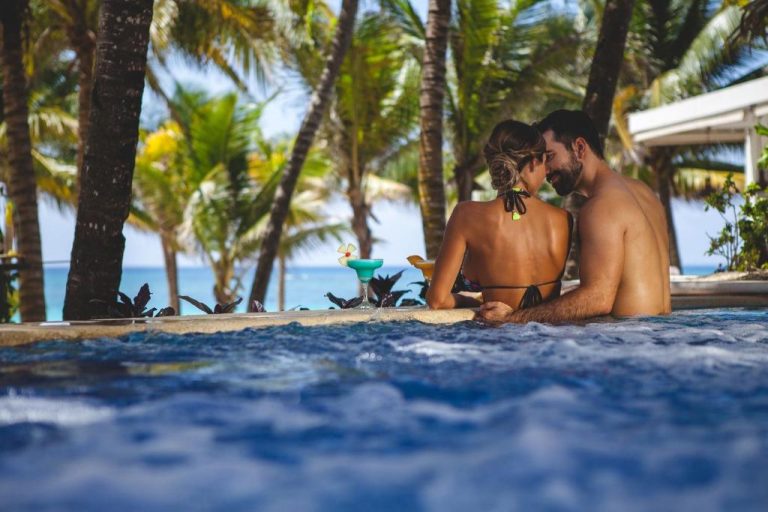 Pareja adulta disfrutando del jacuzzi con cócteles y vista al mar en Catalonia Royal Tulum